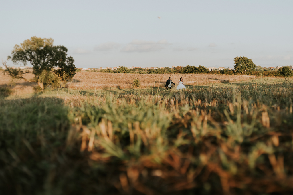 sposi camminano sul prato al tramonto del giorno del matrimonio a roma