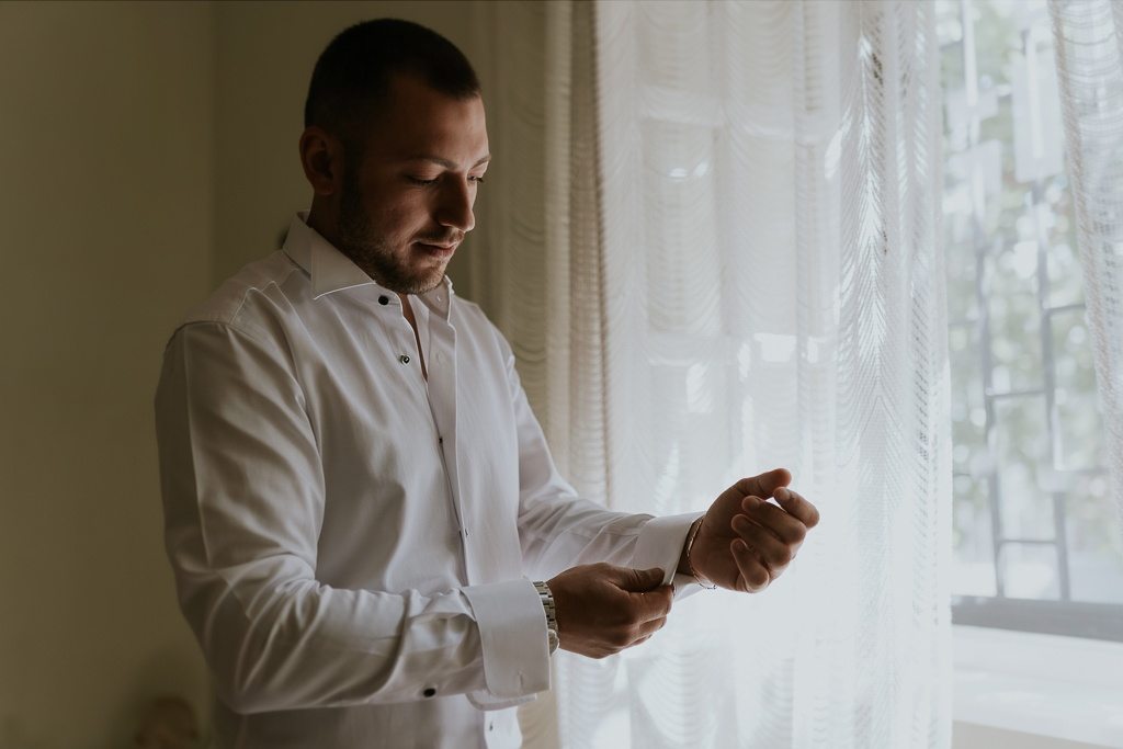 lo sposo si abbottona la camicia per il suo matrimonio a roma