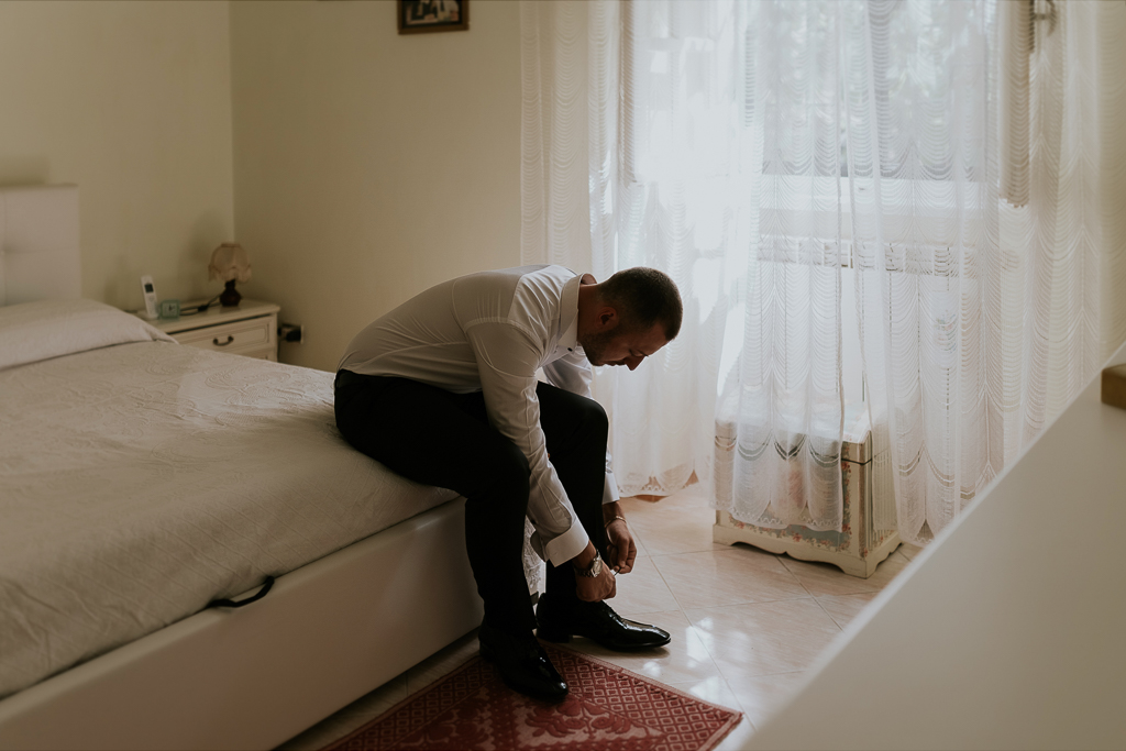 lo sposo allaccia le scarpe per il matrimonio a roma