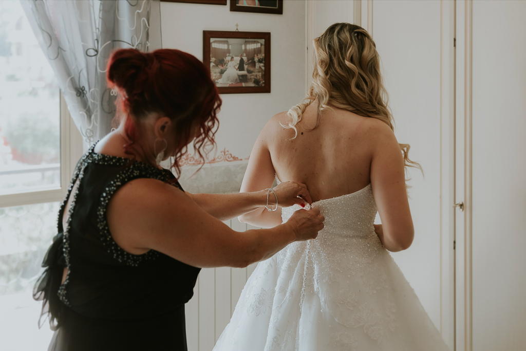 mamma aiuta la sposa per chiudere il vestito