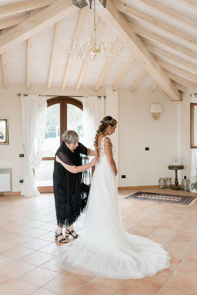 la mamma chiude il vestito della sposa